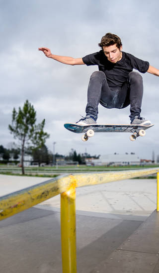 Jongen springt met  skateboard op ballustrade